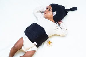 baby on bed wearing noir belly band and top knot hat