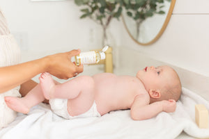 Pouring a baby massage oil on baby's tummy.
