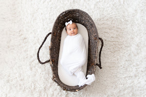 baby in basket wrapped in pearl swaddle