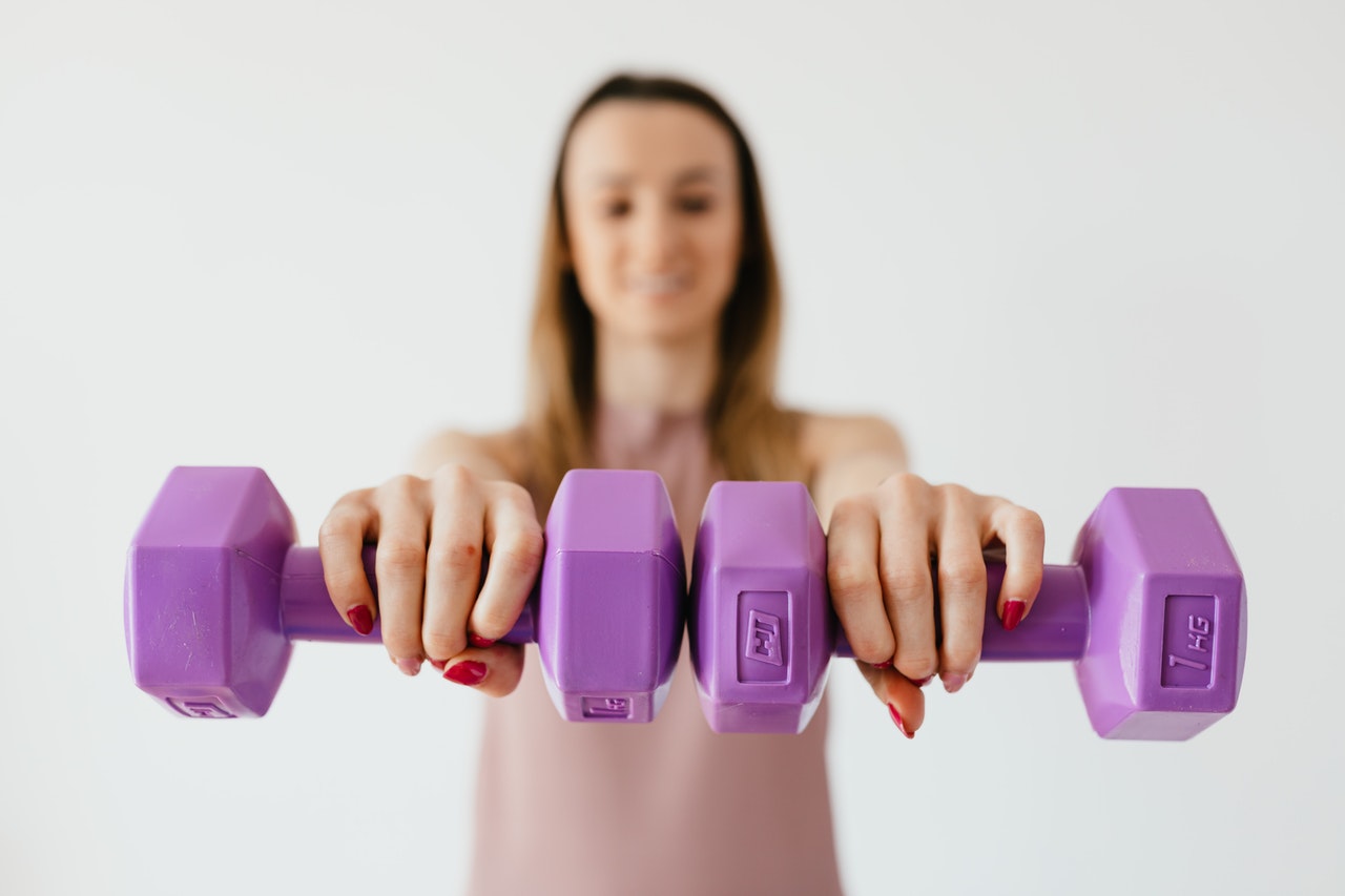 Woman holding purple dumbbells. 
