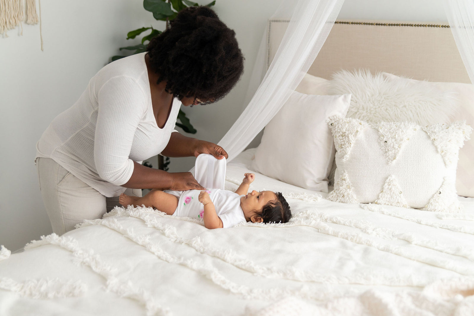 mom putting on a memeeno belly band for gas and colic relief on baby on bed
