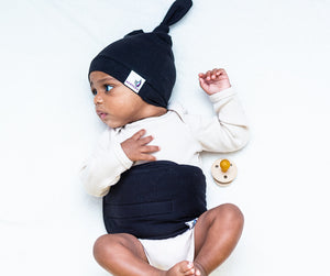 baby on bed wearing noir belly band and top knot hat