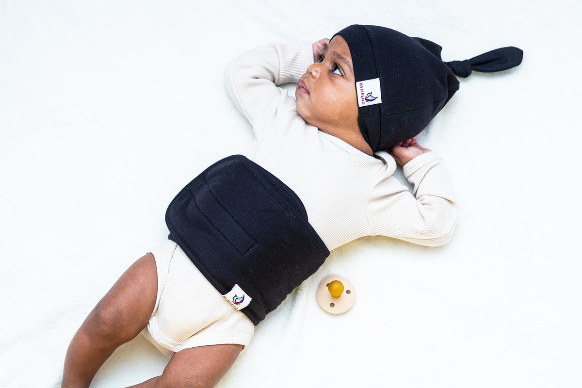 baby on bed wearing noir belly band and top knot hat