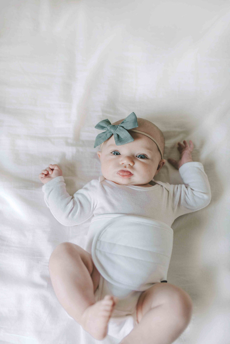 baby on bed wearing Baby belly band for belly button colic, gas, colic remedy white for boy or girl