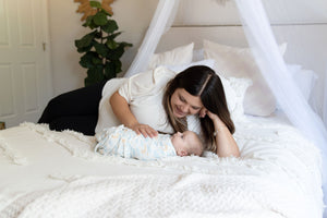 mom and baby swaddled in luna swaddle blanket on a bed