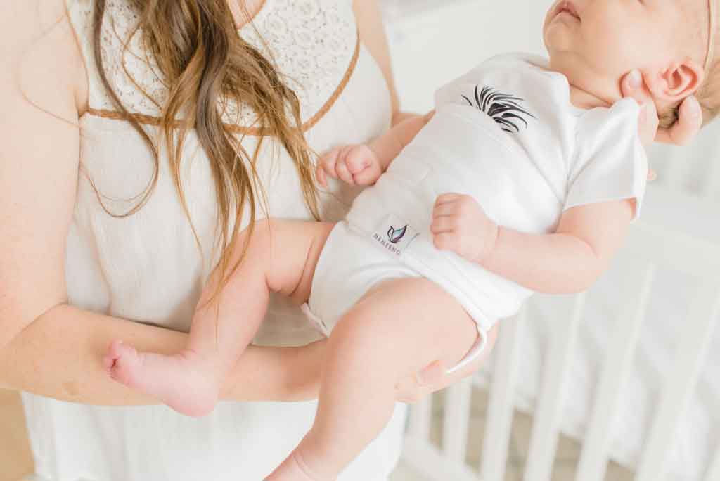 mom holding baby in white pearl belly band