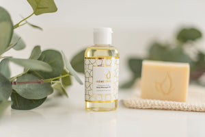 Baby massage oil, all-natural olive oil soap and a sisal soap pouch with leaves as a background.