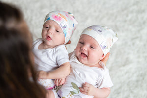 mom holding two smiling babies wearing memeeno organic cotton belly bands and hats