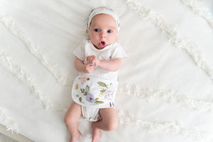  baby on bed wearing top knot hat and organic cotton baby belly band darling, with florals