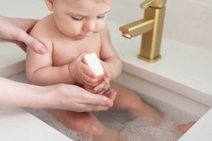 baby holding memeeno olive oil soap in sink