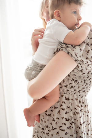 mom holding baby wearing baby in basket wearing organic cotton white memeeno baby belly bloomer