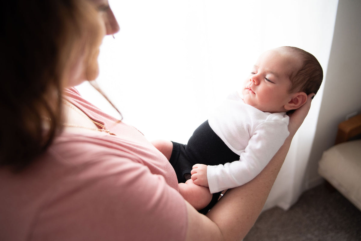 mom holding baby wearing organic cotton black memeeno baby belly bloomer