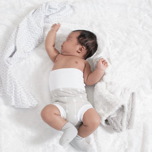 baby stretching on bed wearing baby in basket wearing organic cotton white memeeno baby belly bloomer