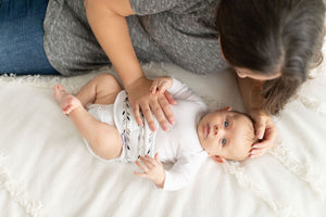 mom lying down with baby wearing a memeeno baby belly band for gas and colic relief with feathers print