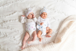 two babies wearing aurelia jellyfish colic belt and top knot hat and ceta whale colic band and top knot hat that are made of organic cotton