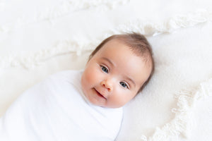 baby smiling in white swaddle by memeeno