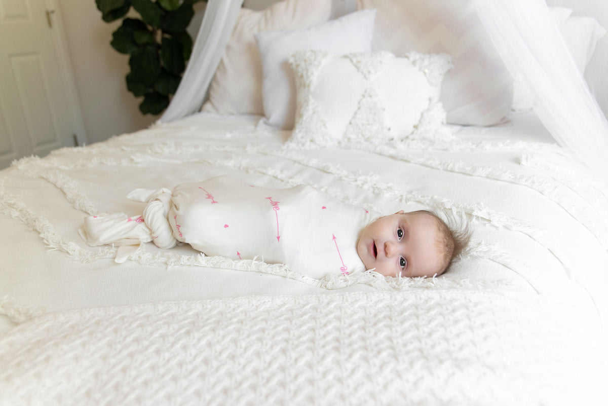 baby swaddled in love her blanket on bed