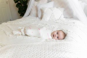 baby swaddled in love her blanket on bed